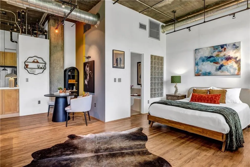 Bedroom with a high ceiling, wood finished floors, and rail lighting