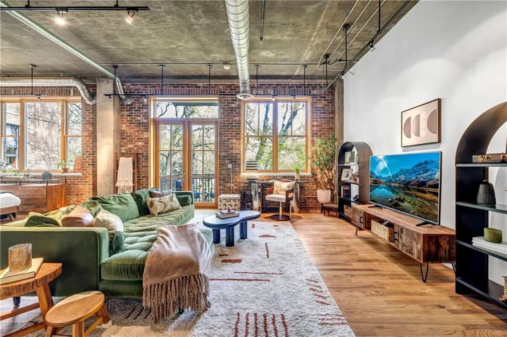 Living area with brick wall, wood finished floors, and rail lighting