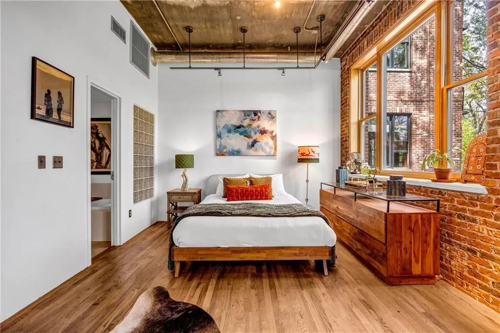 Bedroom featuring wood finished floors, a high ceiling, and brick wall