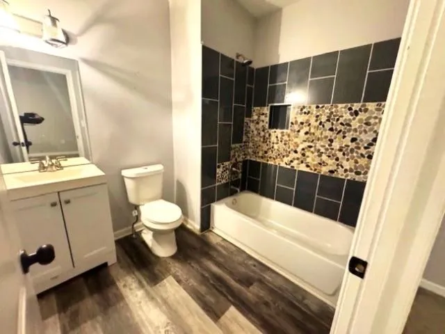 Full bathroom with tiled shower / bath, wood-type flooring, toilet, and vanity