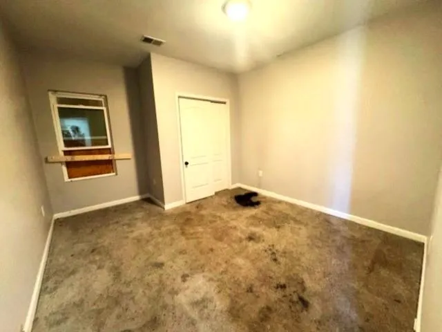 Unfurnished bedroom with a closet and dark colored carpet