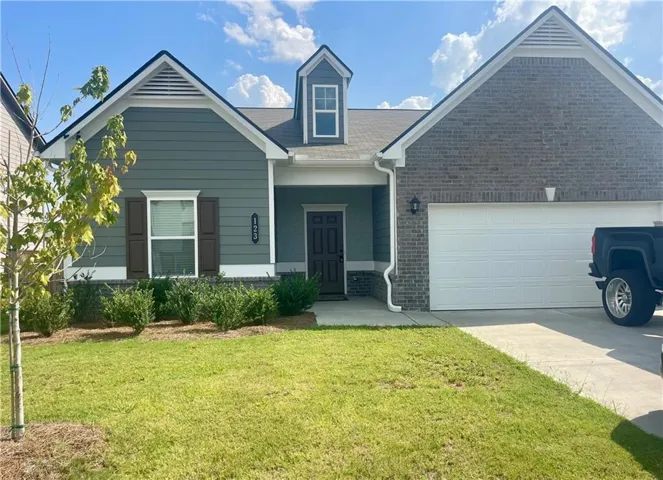Exterior featuring a combination of brick and siding, a dormer window, an attached garage, a covered entry, and established landscaping