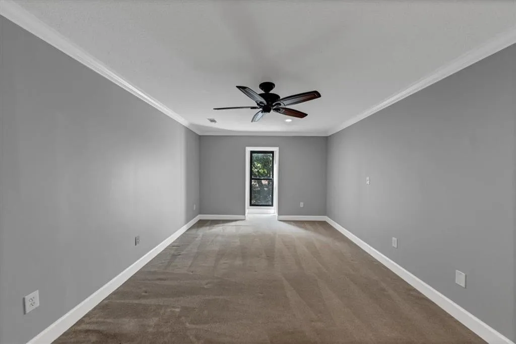 Generous Owner's Bedroom with crown molding, light carpet, and a ceiling fan