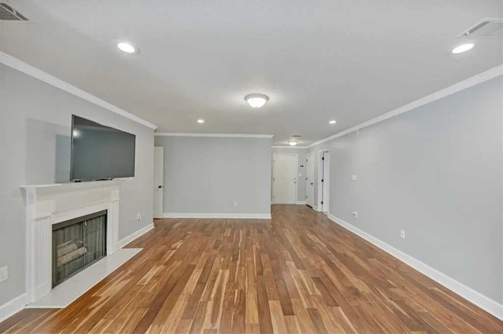 Living room featuring crown molding, wood  floors, recessed lighting, and a fireplace