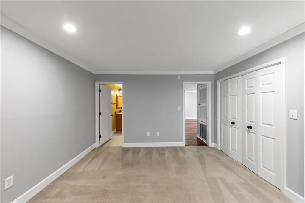 Unfurnished bedroom featuring light carpet, crown molding, a closet, and recessed lighting