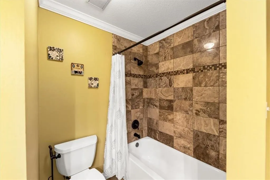Second Bedroom Ensuite featuring tiled shower / bath combo, crown molding