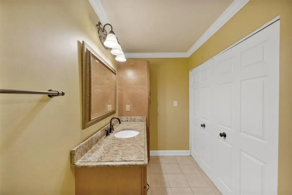 Bathroom with light tile patterned flooring, ornamental molding, and vanity