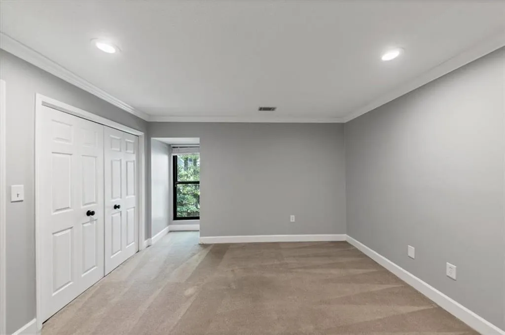 Generous Second bedroom with dual closets, light  carpet, crown molding, and recessed lighting