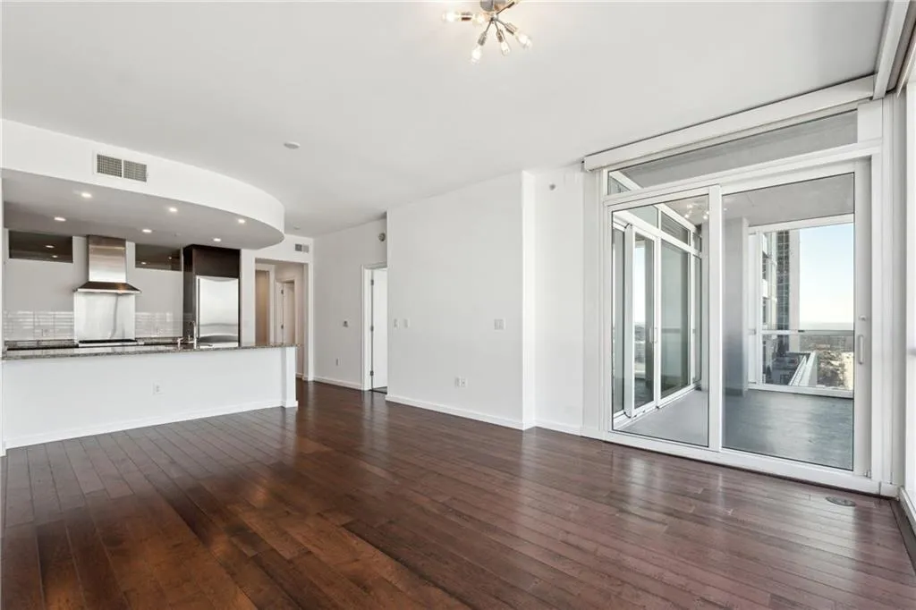 Unfurnished living room with visible vents, dark wood finished floors, baseboards, and an inviting chandelier