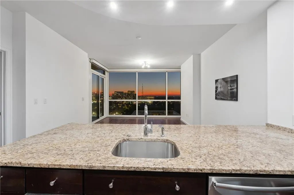 Kitchen with light stone countertops, dark brown cabinetry, a sink, and dishwasher