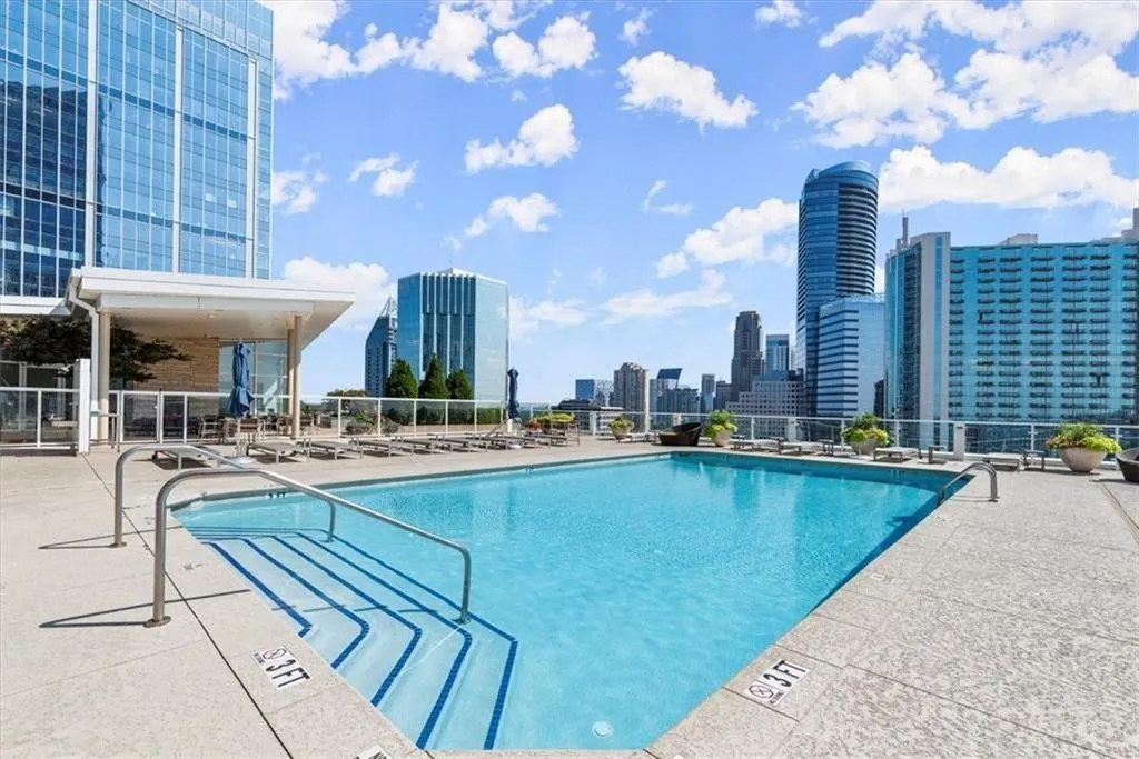 Community pool featuring a patio area, fence, and a city view