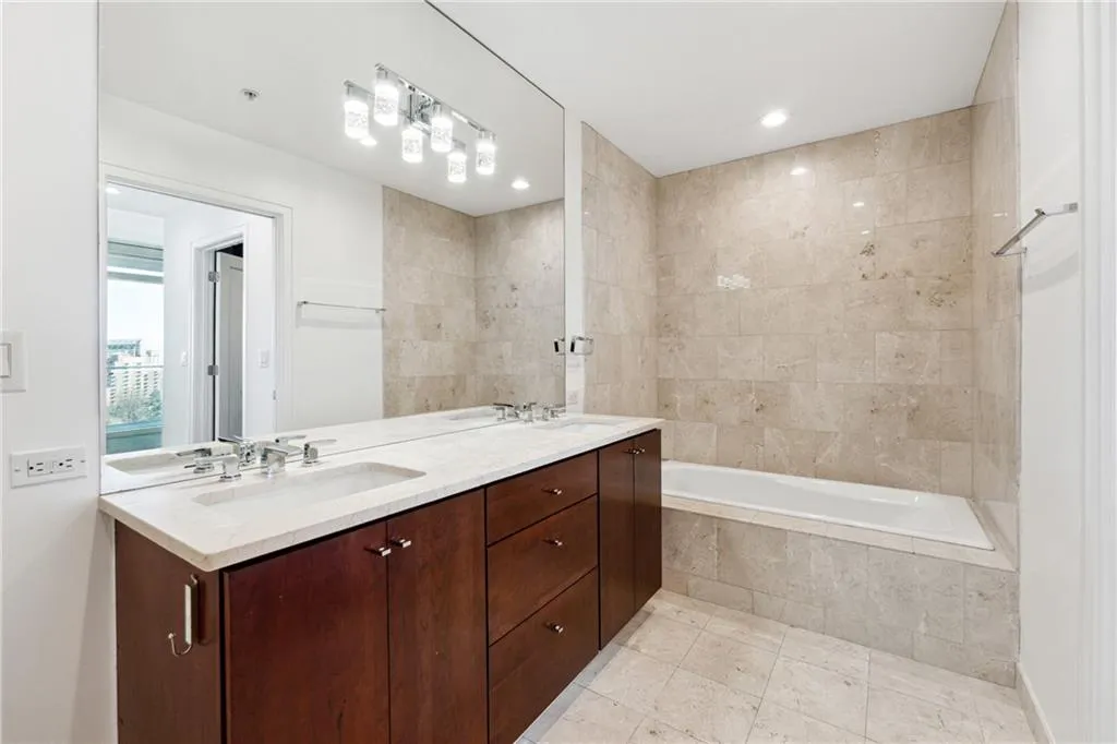 Full bathroom with tiled tub, tile patterned flooring, a sink, and double vanity