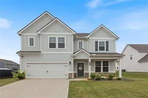 Two-story exterior with light blue siding, a covered front porch, an attached garage, and a concrete driveway