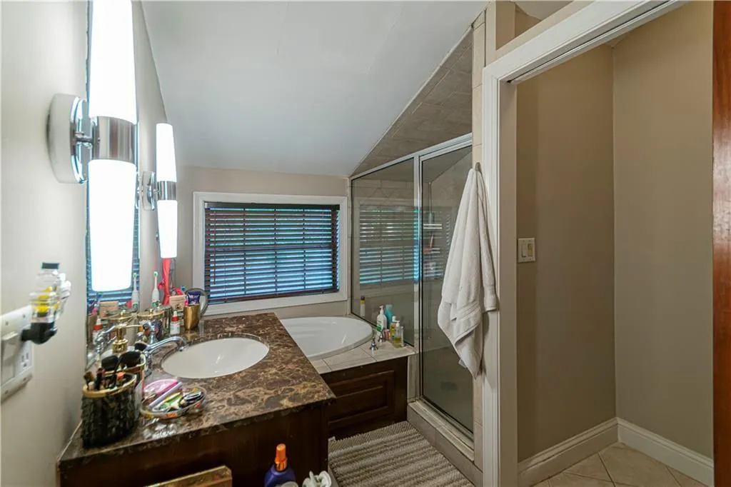 Full bath featuring a garden tub, vanity, a stall shower, tile patterned floors, and lofted ceiling