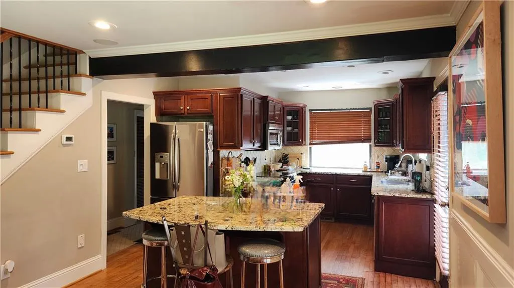 Kitchen with a sink, appliances with stainless steel finishes, wood finished floors, glass insert cabinets, and crown molding