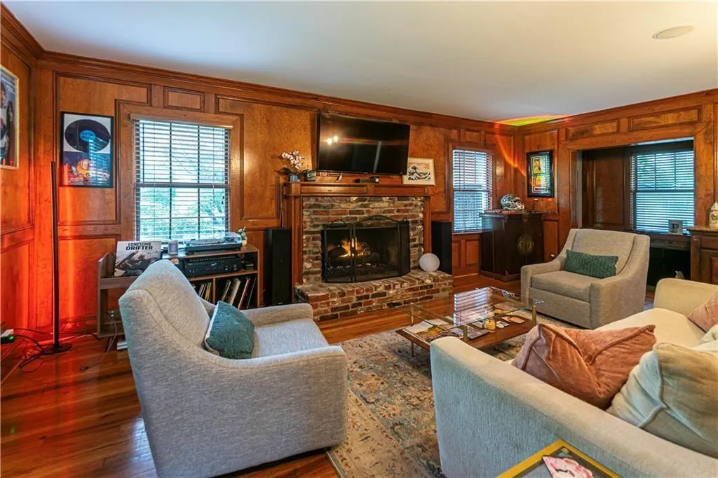 Living room featuring wooden walls, a brick fireplace, and wood finished floors