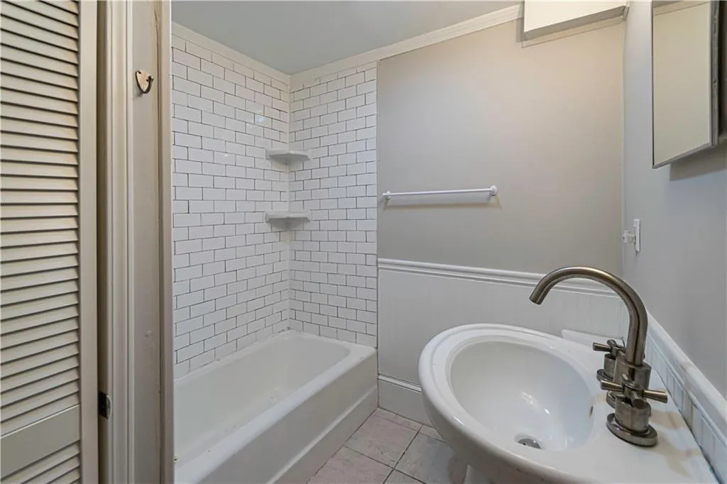Bathroom featuring tile patterned floors, shower / bath combination, a wainscoted wall, and crown molding