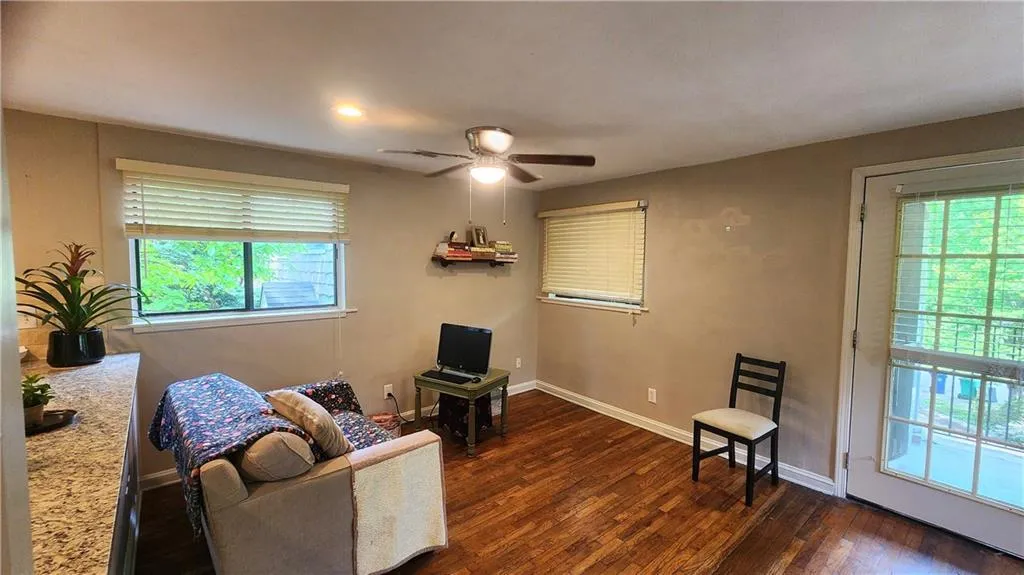 Living area with ceiling fan, dark wood-style floors, and baseboards