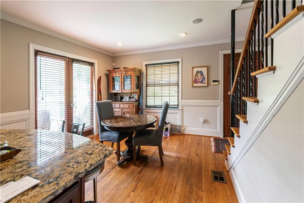 Dining space with stairs, plenty of natural light, crown molding, light wood-type flooring, and wainscoting