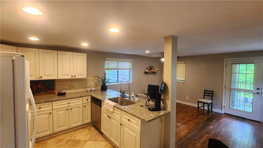 Kitchen featuring freestanding refrigerator, dishwasher, light stone countertops, decorative backsplash, and recessed lighting
