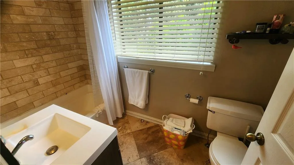 Bathroom with toilet, healthy amount of natural light, a sink, and baseboards