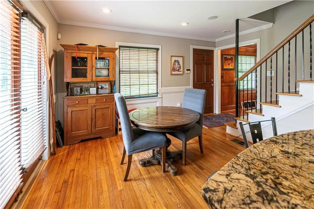 Dining room with a wainscoted wall, light wood-style floors, ornamental molding, plenty of natural light, and stairway