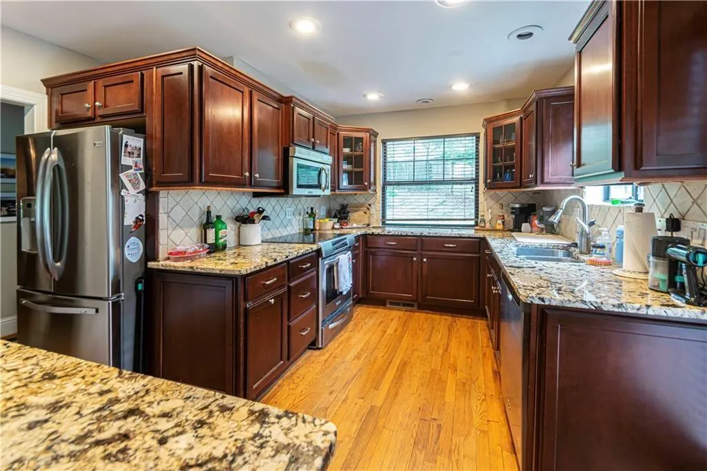 Kitchen with stainless steel appliances, light wood-type flooring, glass insert cabinets, tasteful backsplash, and recessed lighting