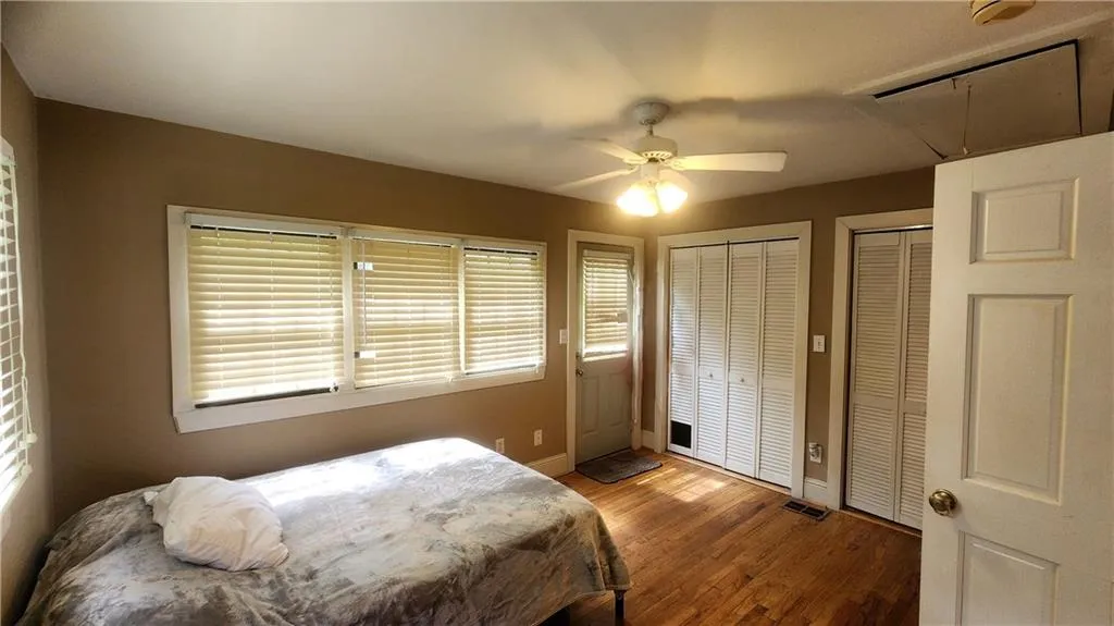 Bedroom with attic access, multiple closets, wood finished floors, baseboards, and ceiling fan