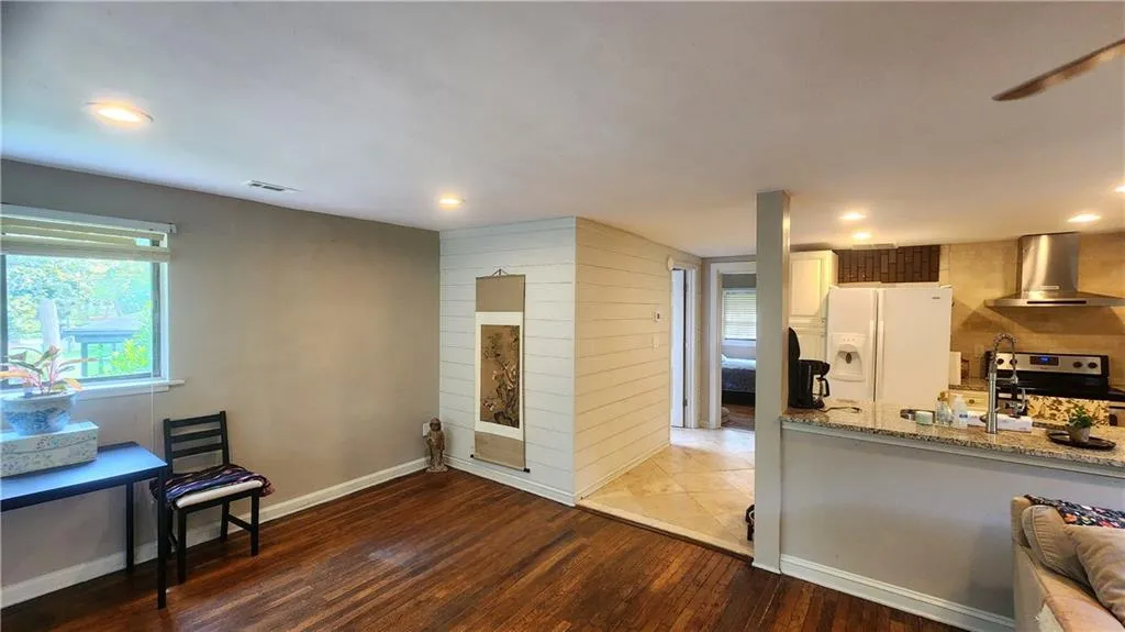 Kitchen featuring wall chimney range hood, white refrigerator with ice dispenser, electric stove, wood finished floors, and a sink