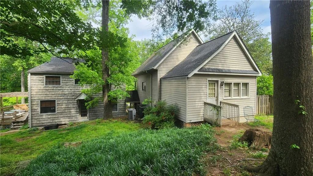 Back of property featuring a shingled roof and central AC unit