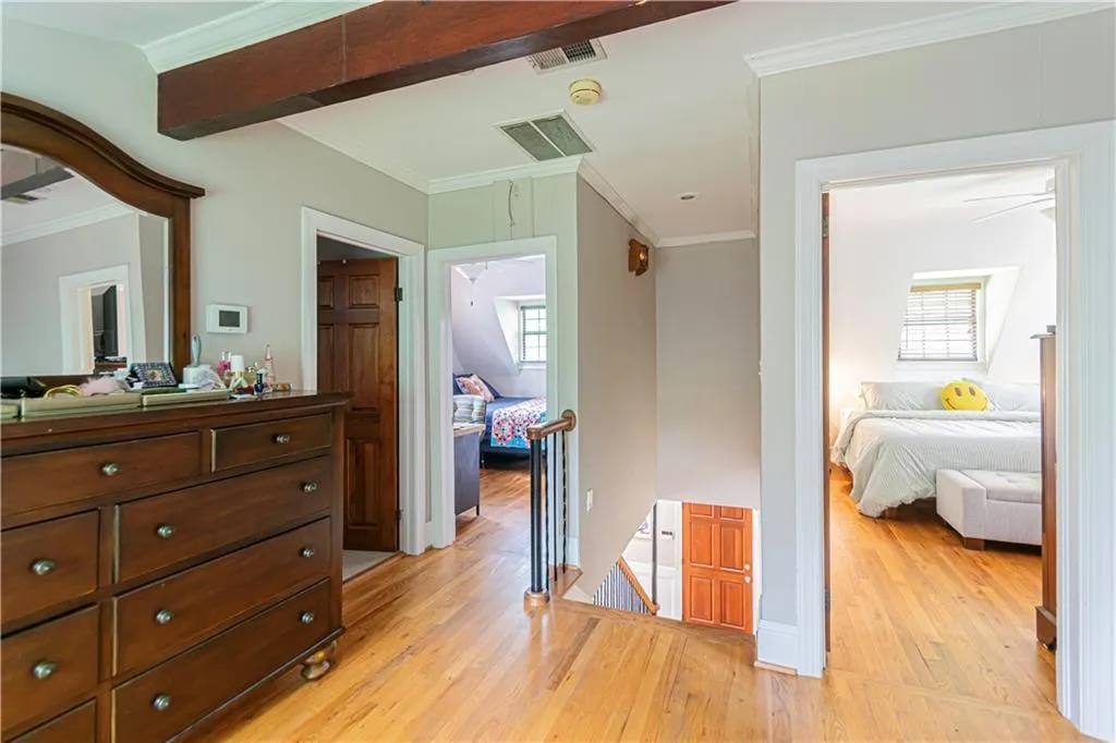 Corridor with an upstairs landing, light wood finished floors, and crown molding