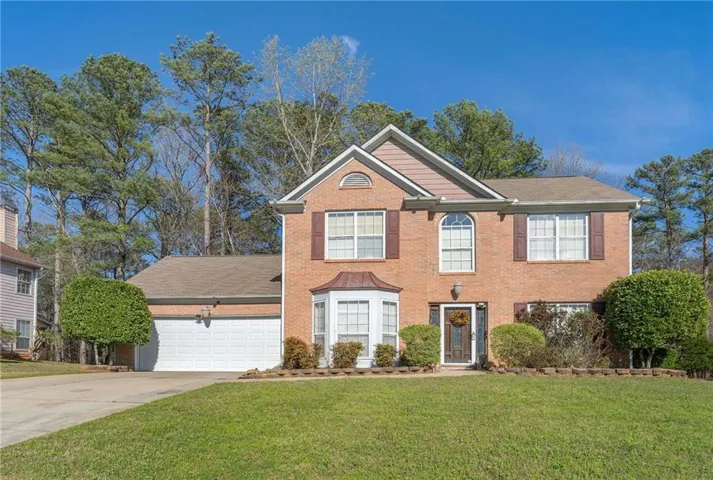 View of front of home featuring a front yard, driveway, an attached garage, and brick siding