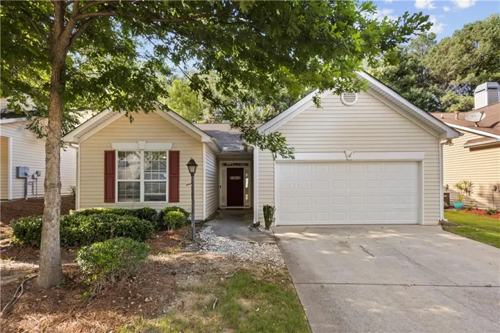 Cream-colored siding exterior featuring a white garage door, red window shutters, and a dark red front door
