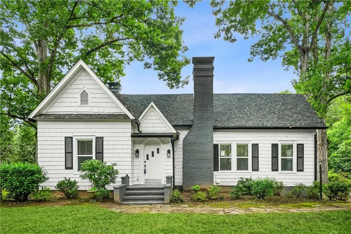 Charming white exterior with shingle siding and dark shutters