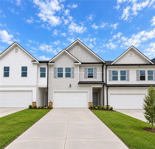 Contemporary townhome exterior with mixed siding, gabled rooflines, and individual garage doors