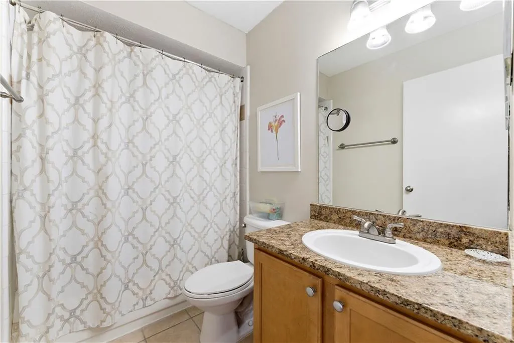 Full bath featuring vanity, light tile patterned floors, and shower / tub combo with curtain