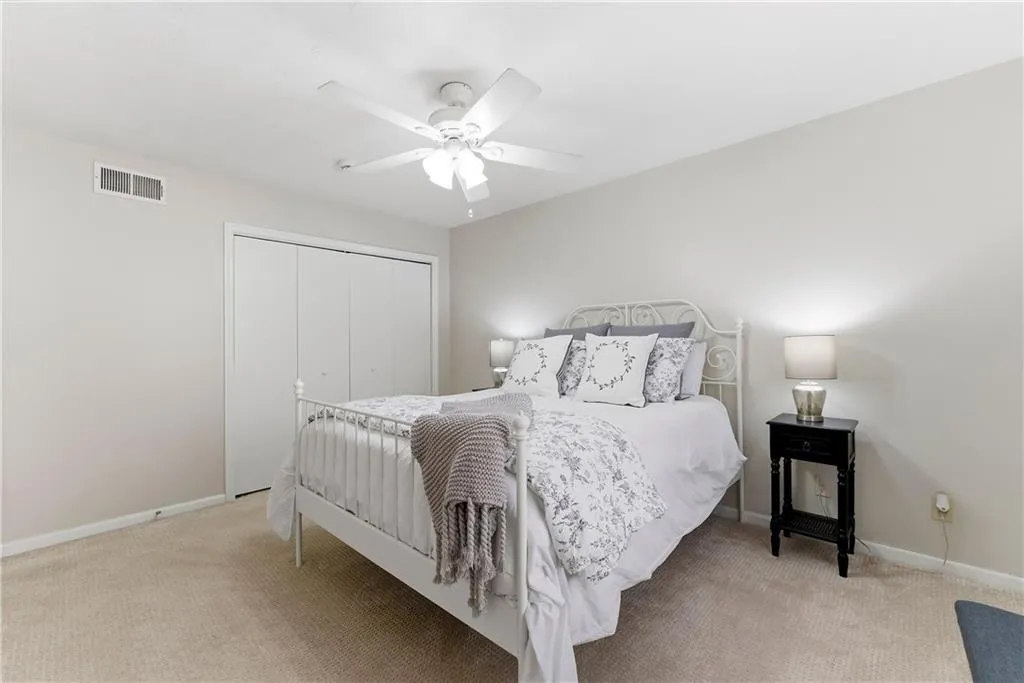 Bedroom featuring light colored carpet, a closet, and a ceiling fan