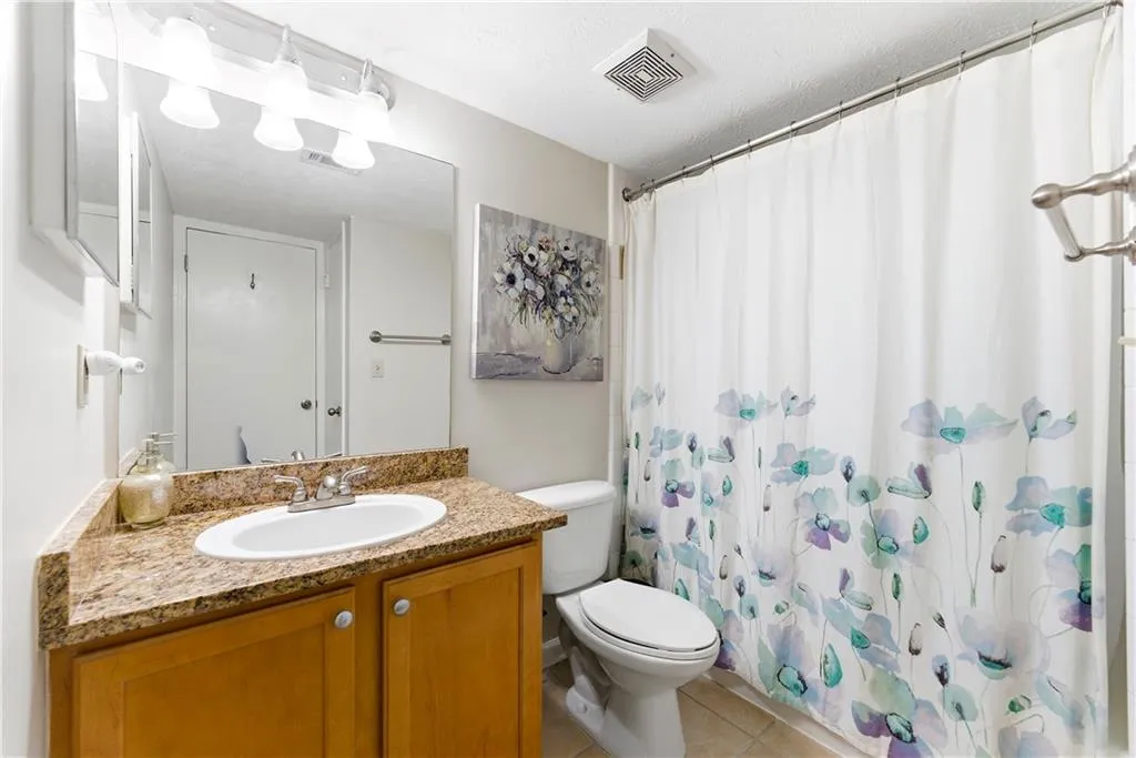 Full bath featuring vanity, curtained shower, light tile patterned flooring, and a textured ceiling