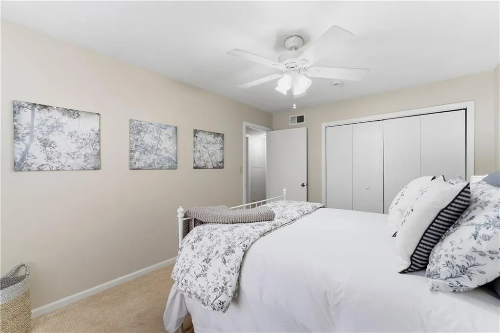 Bedroom with ceiling fan, a closet, and light carpet