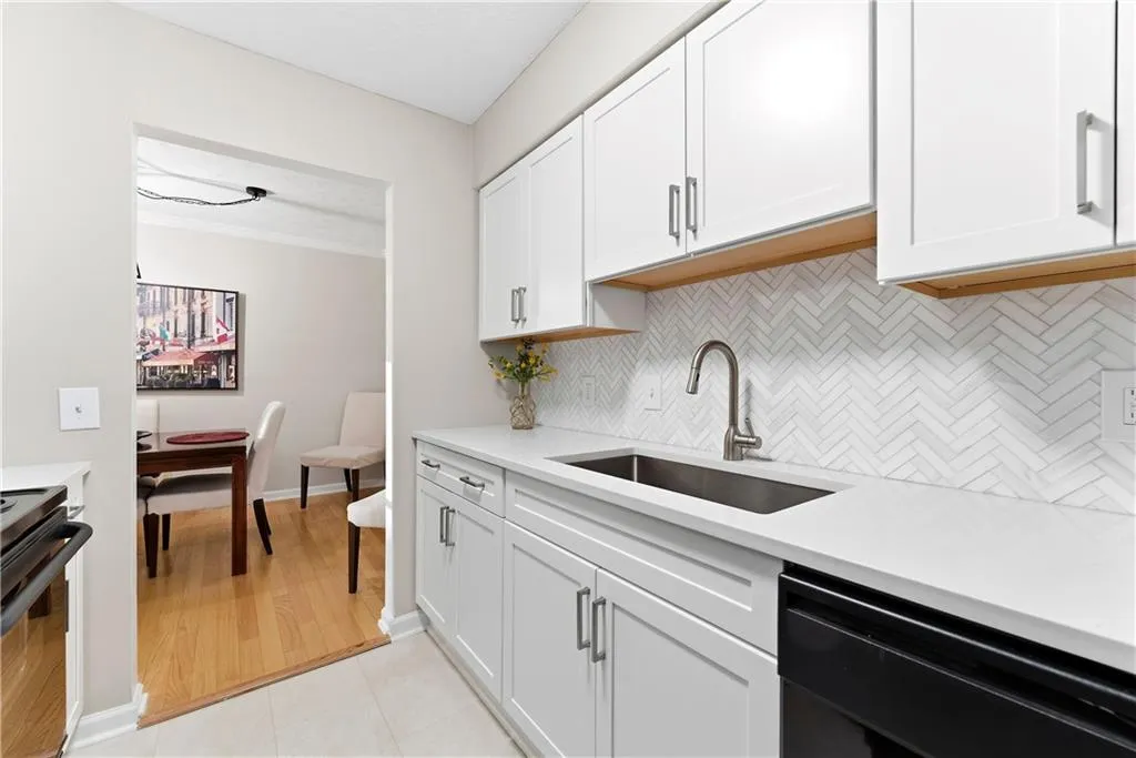 Kitchen featuring black appliances, tasteful backsplash, white cabinetry, crown molding, and light tile patterned flooring