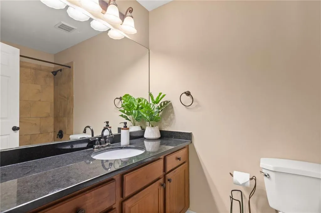 Bathroom featuring beautiful black countertops, and a wide vanity with extensive cabinet and counter space.