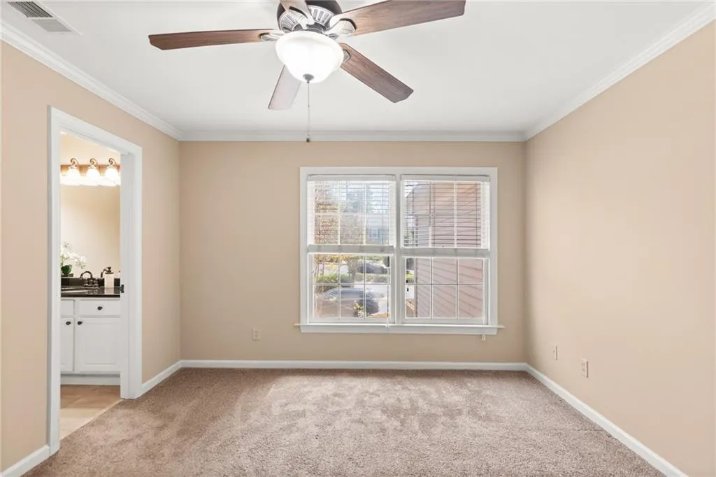 As we head upstairs, we see Bedroom 1. Alongside a large window, light carpet, and a classy fan, Bedroom 1 boats a personal bathroom and closet.