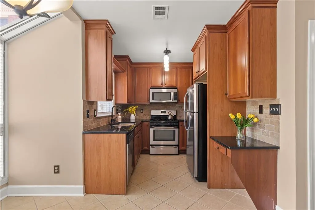 Your beautiful kitchen with stainless-steel appliances, a modern chandelier, and easy clean up tiles -- all complemented with dark stone countertops.
