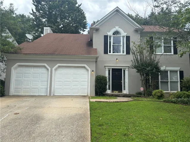 Stucco exterior with a two-car garage, featuring a prominent arched window on the second story