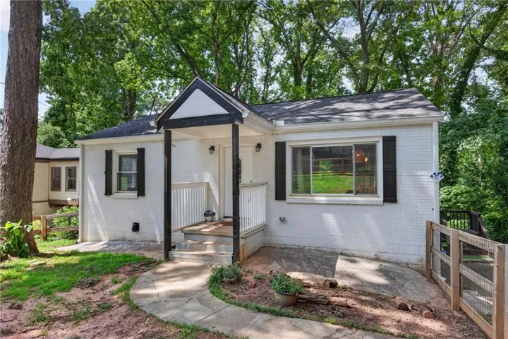 White brick exterior with black shutters and a covered front porch featuring white railings