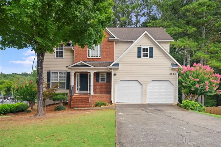 Two-story exterior with brick and siding facade, covered front entry, attached two-car garage, and mature landscaping