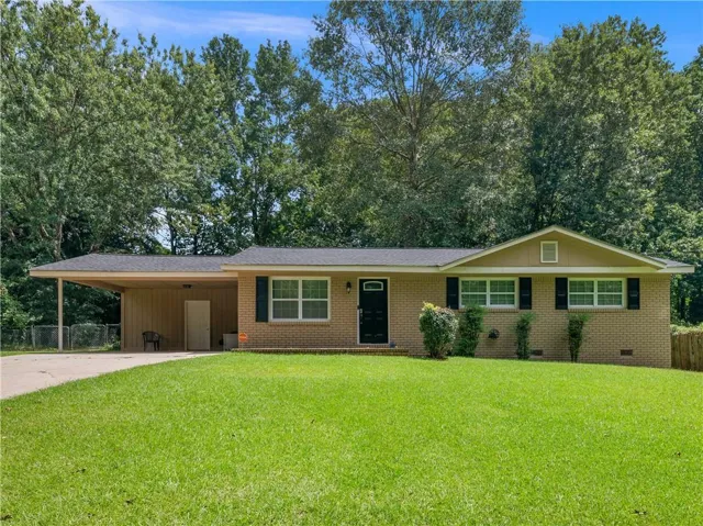 Brick exterior featuring a covered carport, black shutters, and a front gabled accent