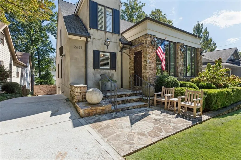 Stucco exterior featuring stacked stone accents, flagstone patio, custom metal railings, and dark shutter details