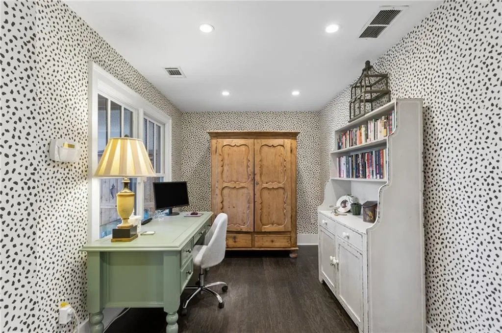 Room featuring patterned wallpaper, dark-toned wood-finish flooring, and recessed ceiling lighting