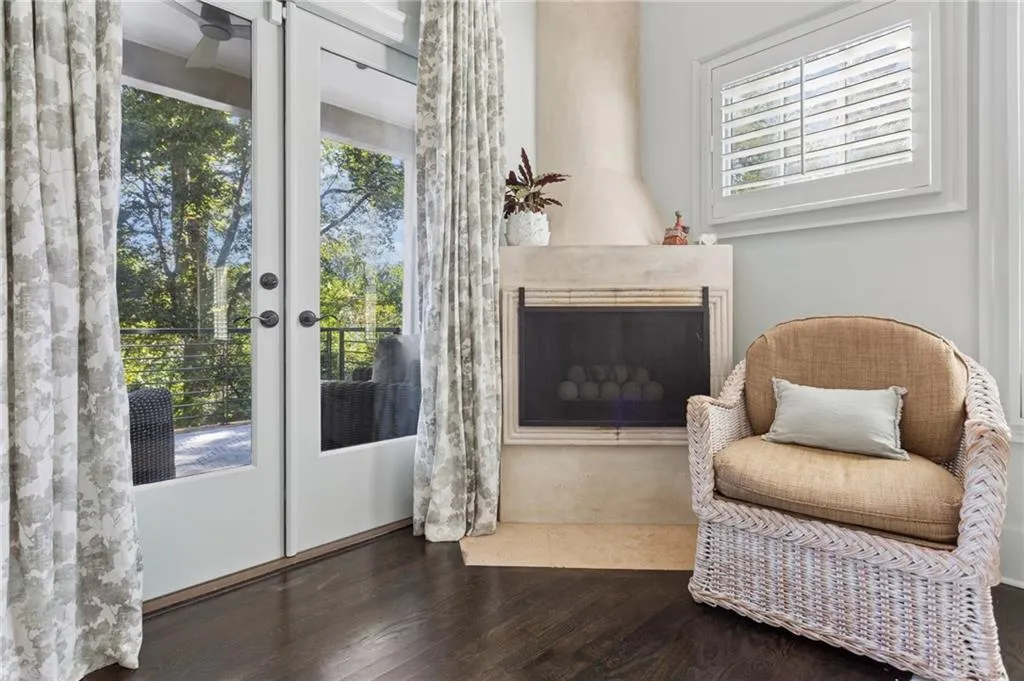 Custom plaster fireplace with integrated hearth, dark wood-finish flooring, full-glass panel doors, and window shutters